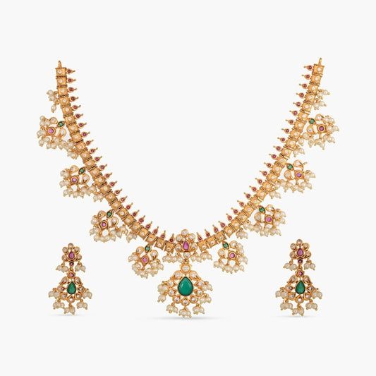 A picture of an Indian artificial jewelry set featuring a gold plated necklace and earrings embellished with pearls and green gemstones.
