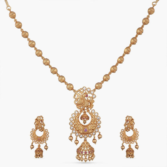 A picture of an Indian artificial jewelry set with an antique gold plated necklace and matching earrings with Cubic Zirconia and red stones.